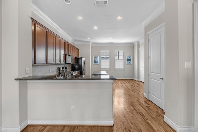 kitchen with stainless steel appliances, backsplash, visible vents, ornamental molding, and light wood-style flooring