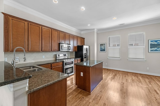kitchen with brown cabinets, stainless steel appliances, a sink, a kitchen island, and tasteful backsplash
