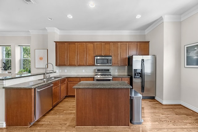 kitchen with dark stone counters, a sink, brown cabinetry, stainless steel appliances, and a kitchen island