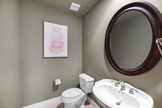 bathroom featuring toilet, a sink, visible vents, and baseboards