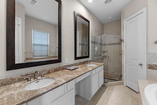 bathroom with a shower stall, visible vents, tiled tub, and a sink