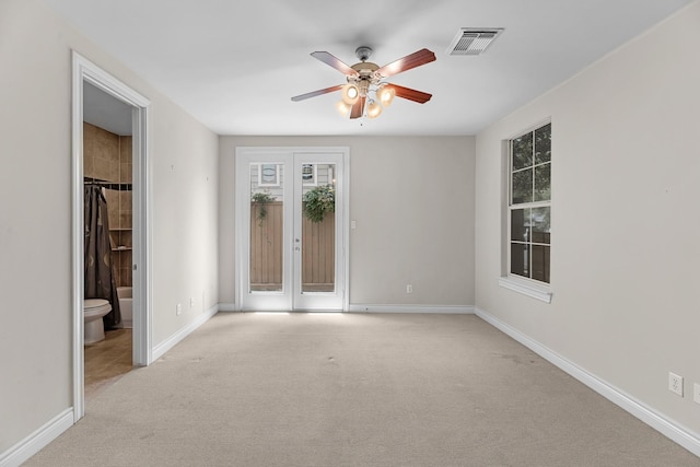 empty room with baseboards, visible vents, carpet floors, and ceiling fan