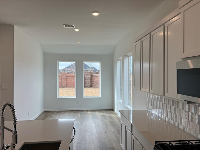 kitchen with visible vents, a sink, stainless steel microwave, and a healthy amount of sunlight