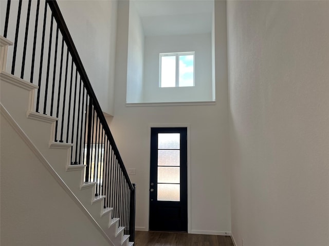 entryway with a high ceiling, wood finished floors, a wealth of natural light, and stairway