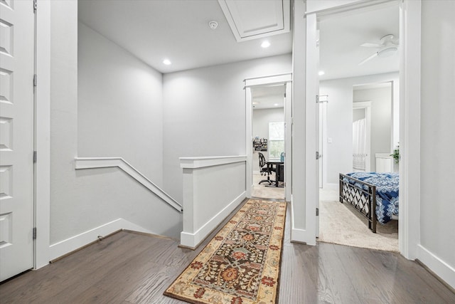 corridor with an upstairs landing, wood finished floors, attic access, baseboards, and recessed lighting