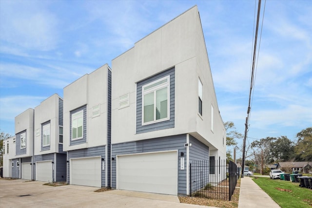 view of home's exterior featuring a garage, a residential view, concrete driveway, and fence