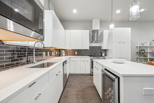 kitchen featuring wall chimney range hood, a sink, modern cabinets, stainless steel appliances, and wine cooler
