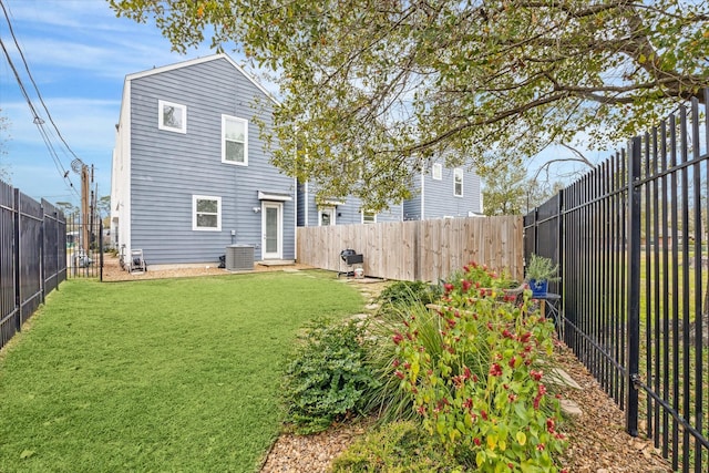 rear view of property featuring a fenced backyard, central AC unit, and a lawn