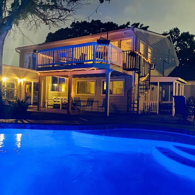 15907 Whispering Falls Ct, Houston, TX 77084 - back of house at night with an outdoor pool, a patio, stairway, and a balcony