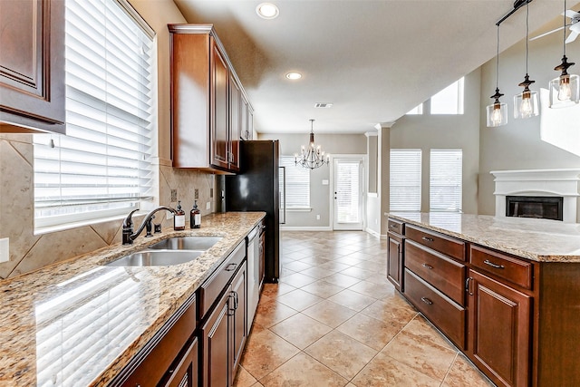 kitchen with stainless steel appliances, light tile patterned floors, a sink, decorative light fixtures, and a chandelier