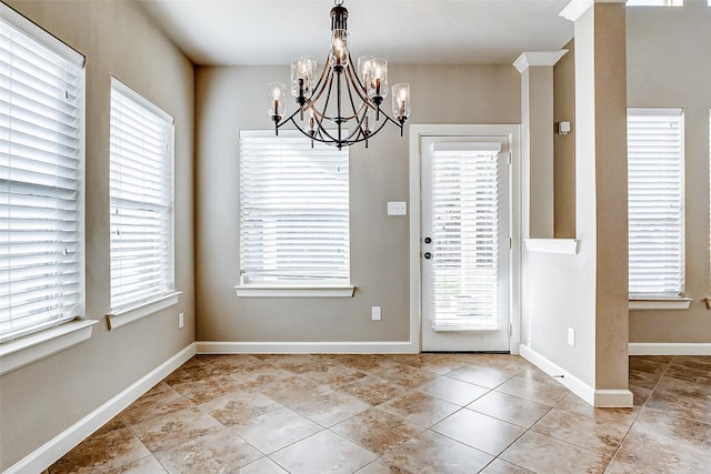 interior space with an inviting chandelier, a healthy amount of sunlight, tile patterned flooring, and baseboards