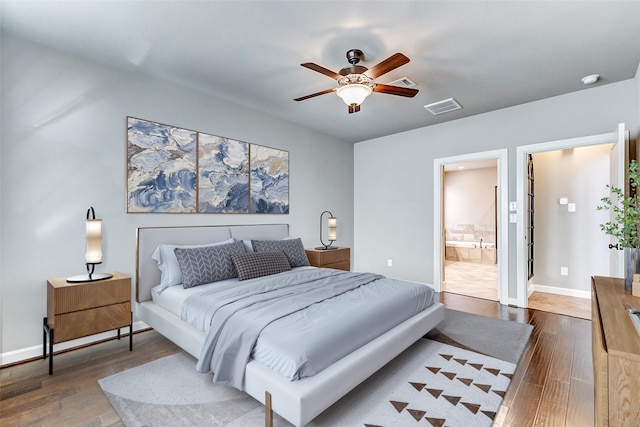 bedroom with ensuite bath, hardwood / wood-style floors, visible vents, and baseboards