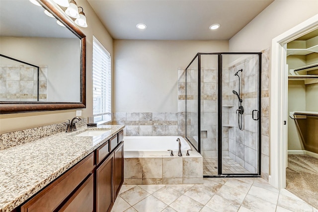 full bath with recessed lighting, a shower stall, vanity, a walk in closet, and a garden tub