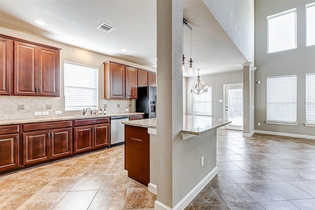 kitchen with stainless steel dishwasher, a sink, an inviting chandelier, decorative backsplash, and black refrigerator with ice dispenser