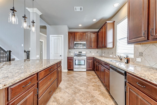 kitchen featuring stainless steel appliances, a sink, visible vents, light stone counters, and hanging light fixtures