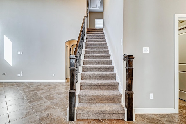 staircase featuring arched walkways, tile patterned floors, and baseboards