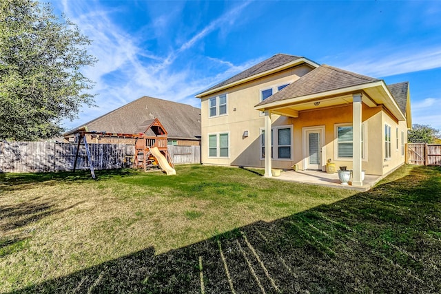 rear view of house with a playground, a fenced backyard, stucco siding, a patio, and a lawn