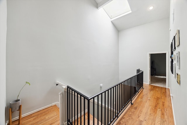 hallway with attic access, baseboards, wood finished floors, and an upstairs landing