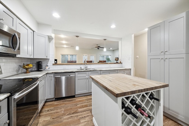kitchen featuring light wood-style flooring, a sink, tasteful backsplash, butcher block counters, and appliances with stainless steel finishes