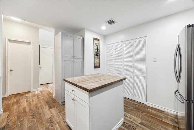 kitchen with visible vents, freestanding refrigerator, recessed lighting, wood finished floors, and butcher block counters