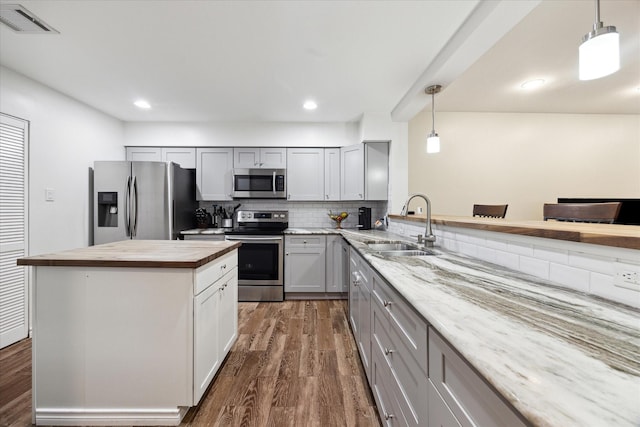 kitchen with stainless steel appliances, a sink, wooden counters, and dark wood finished floors