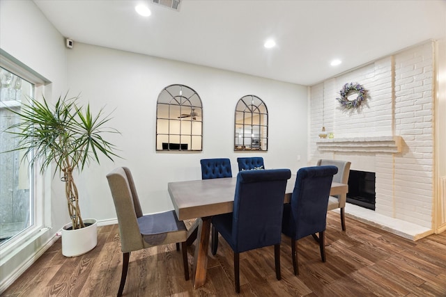 dining space featuring visible vents, baseboards, recessed lighting, a brick fireplace, and wood finished floors