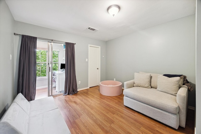 living area featuring baseboards, light wood-style floors, and visible vents