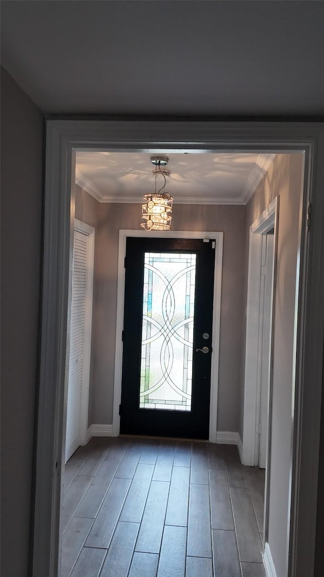 entryway featuring a chandelier, crown molding, wood finished floors, and baseboards