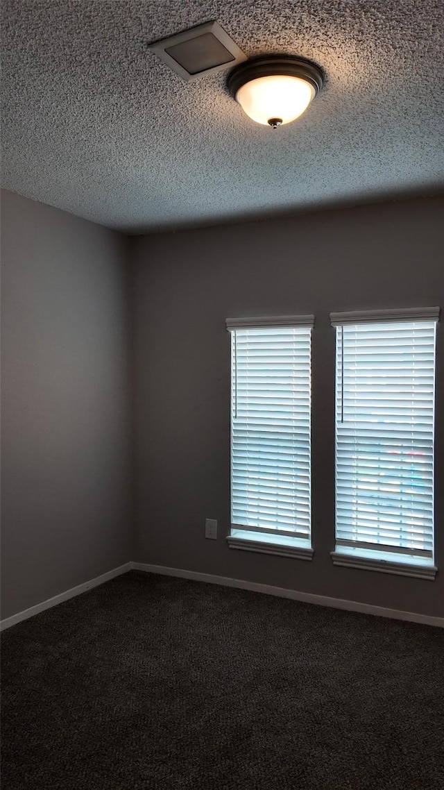 spare room with carpet floors, baseboards, and a textured ceiling