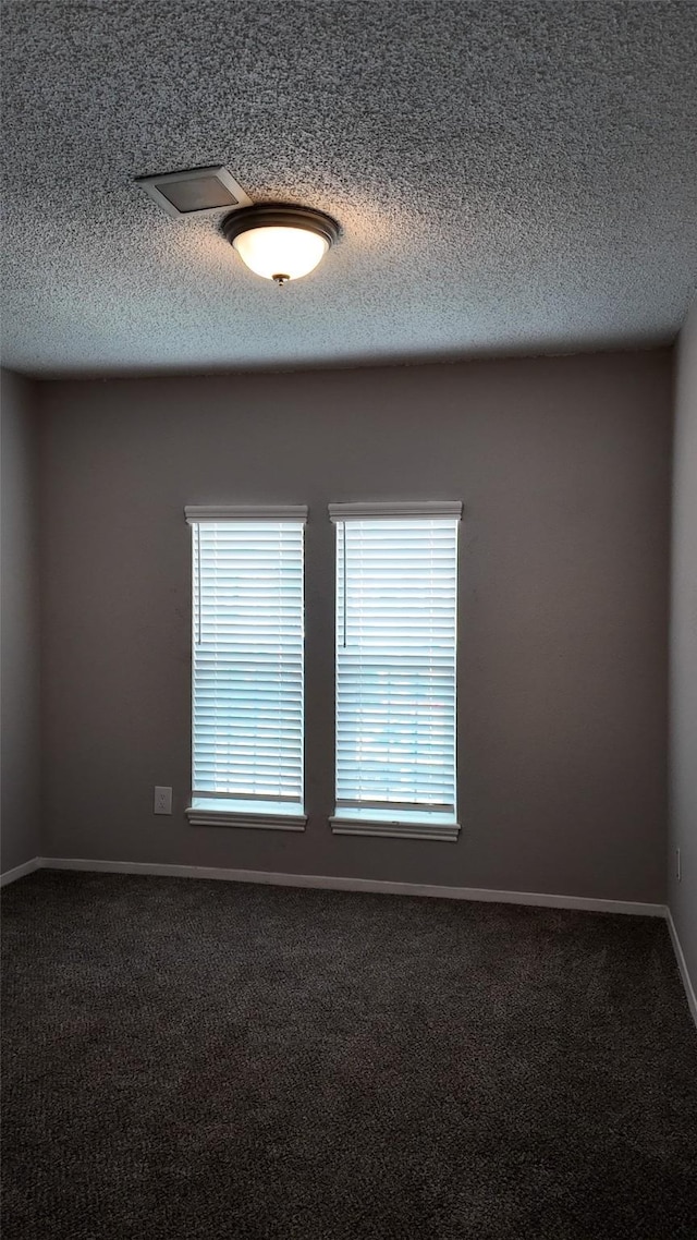 spare room featuring carpet flooring, a textured ceiling, and baseboards