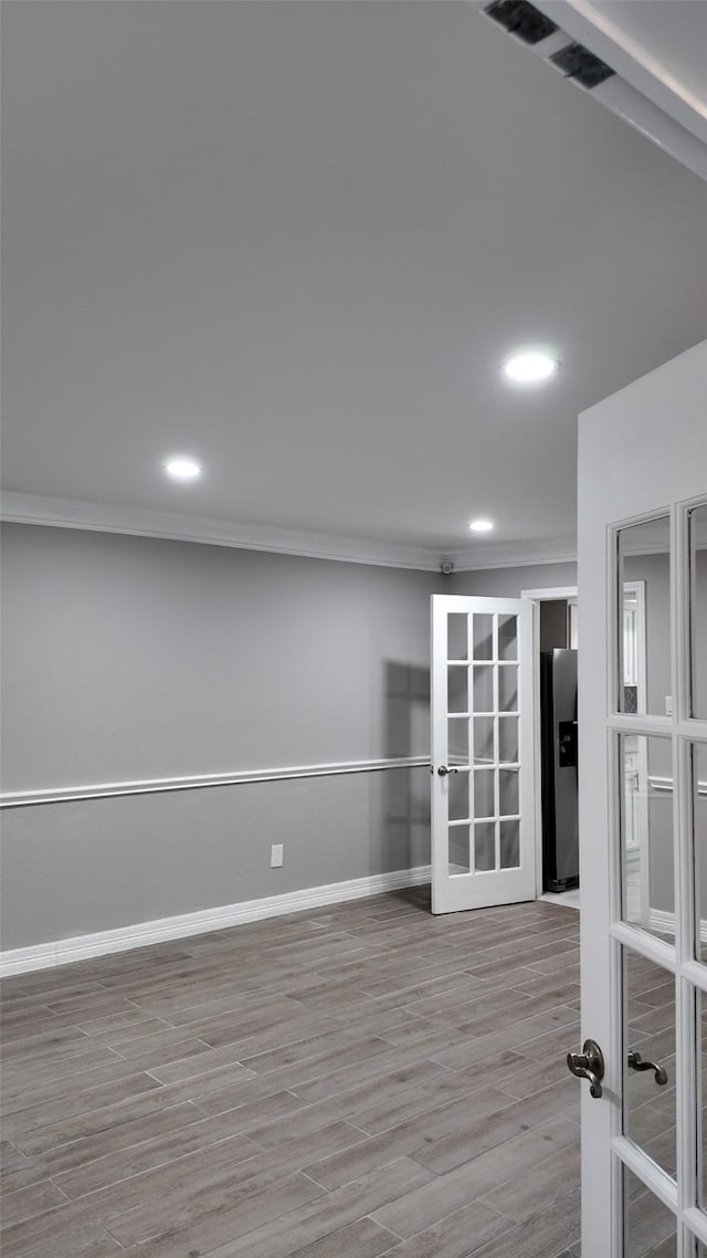 empty room featuring crown molding, recessed lighting, wood finished floors, french doors, and baseboards