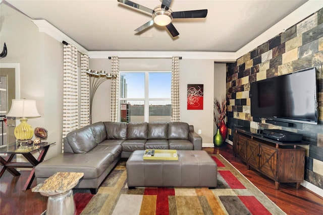 living area with wood finished floors, a ceiling fan, baseboards, and ornamental molding