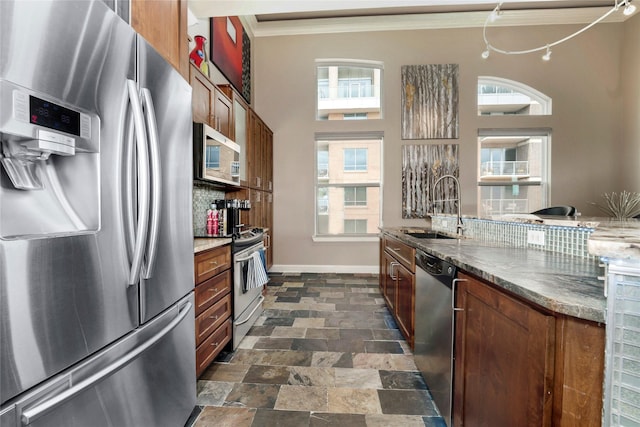 kitchen with a sink, crown molding, baseboards, decorative backsplash, and appliances with stainless steel finishes