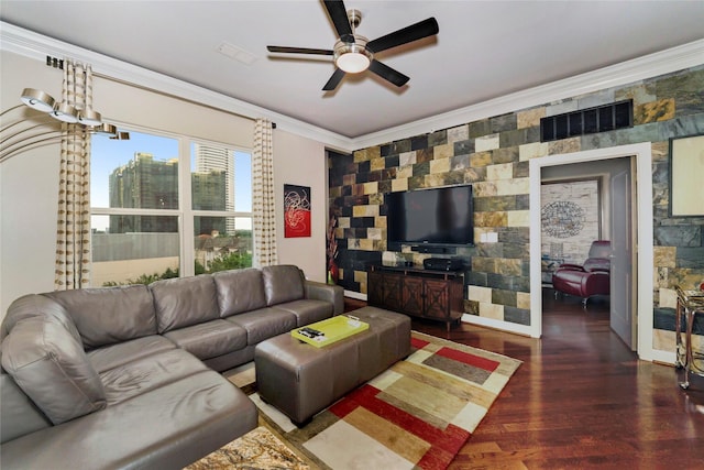 living room with wood finished floors, visible vents, a ceiling fan, an accent wall, and crown molding
