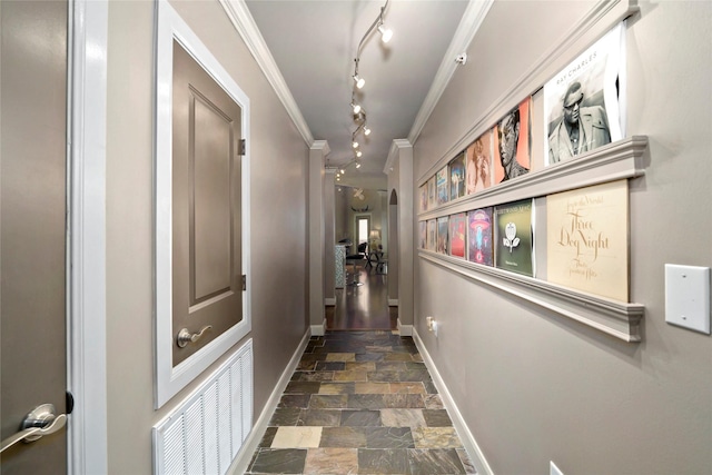 corridor with track lighting, stone finish flooring, baseboards, ornamental molding, and visible vents