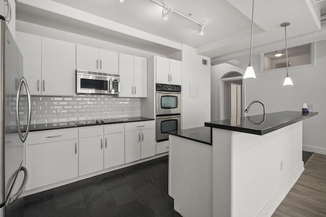 kitchen featuring dark countertops, tasteful backsplash, hanging light fixtures, stainless steel appliances, and white cabinets