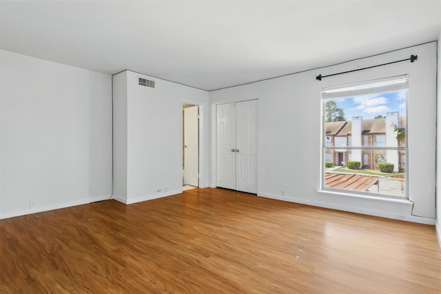 spare room with light wood-type flooring, baseboards, and visible vents
