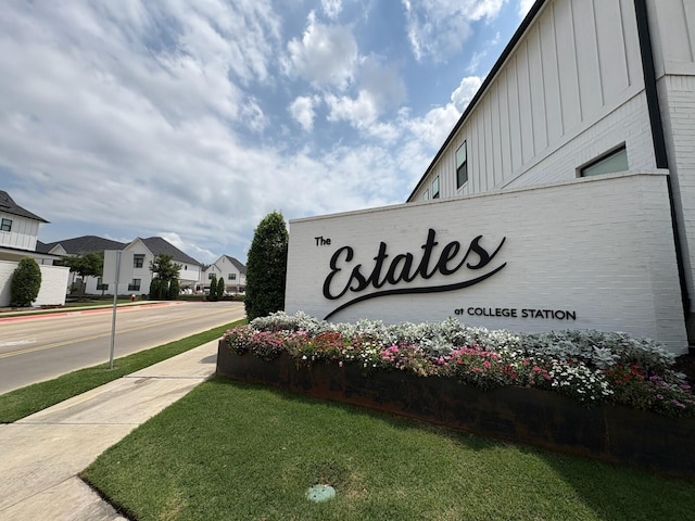 community sign featuring a residential view and a yard
