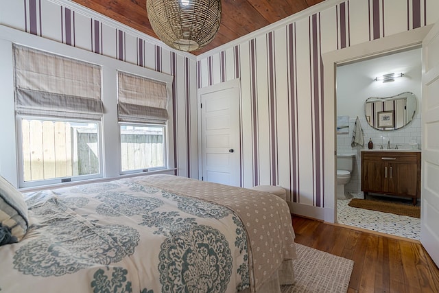 3825 Avenue N 1/2 Ave N Unit 1/2, Galveston, TX 77550 - bedroom featuring wallpapered walls, a sink, connected bathroom, and wood-type flooring