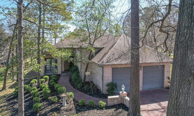 view of front of house with brick siding, an attached garage, driveway, and a shingled roof