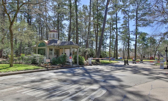 view of street with a gated entry, curbs, and street lights