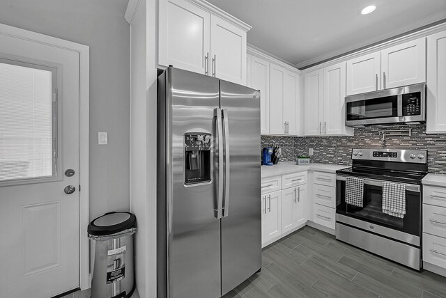 4903 Mallow St Unit Ab, Houston, TX 77033 - kitchen featuring dark wood-style floors, light countertops, decorative backsplash, appliances with stainless steel finishes, and white cabinetry