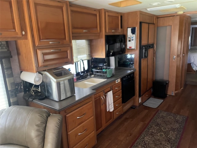 kitchen with dark wood-type flooring, black microwave, brown cabinetry, and a sink