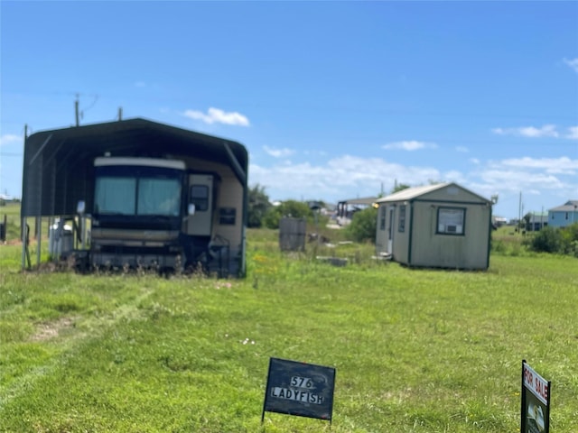 view of yard with a carport, an outdoor structure, and a shed
