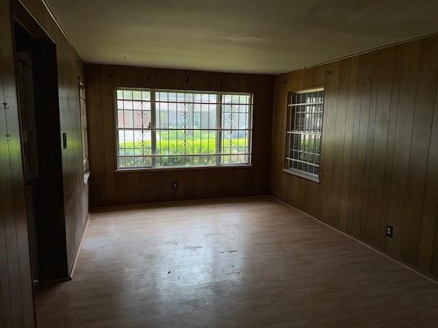 unfurnished room with wood finished floors and wooden walls