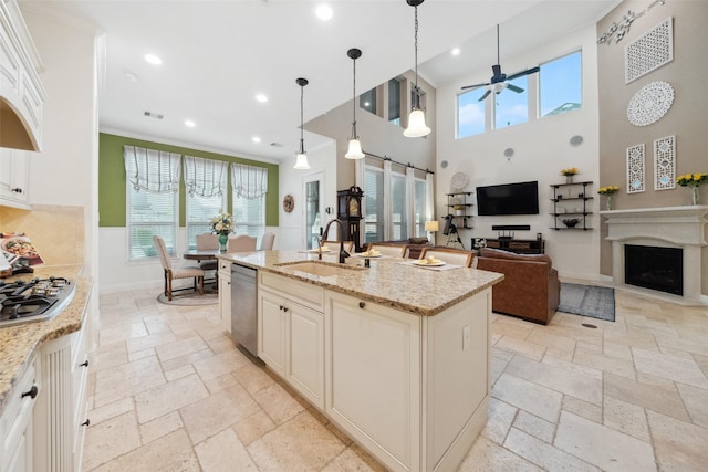 kitchen featuring stone tile flooring, a sink, a ceiling fan, stainless steel appliances, and a fireplace