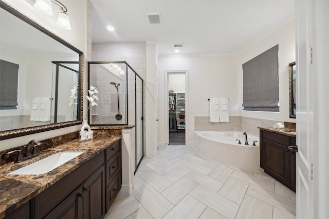 bathroom with a shower stall, crown molding, vanity, a garden tub, and a walk in closet