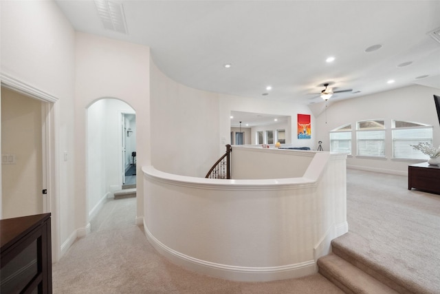 corridor featuring light carpet, an upstairs landing, baseboards, arched walkways, and recessed lighting