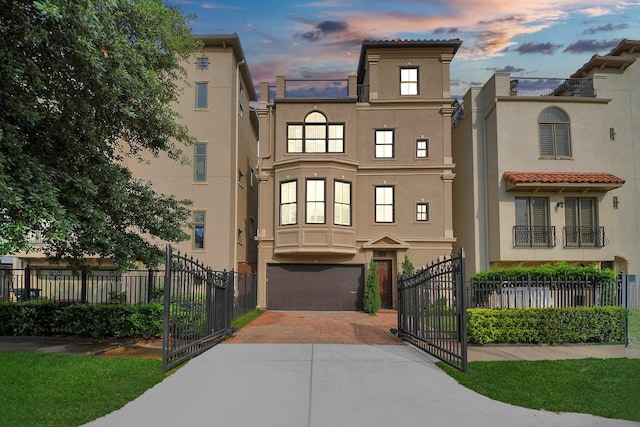 view of building exterior featuring decorative driveway, fence, and a garage