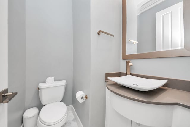 bathroom featuring baseboards, a sink, marble finish floor, and toilet